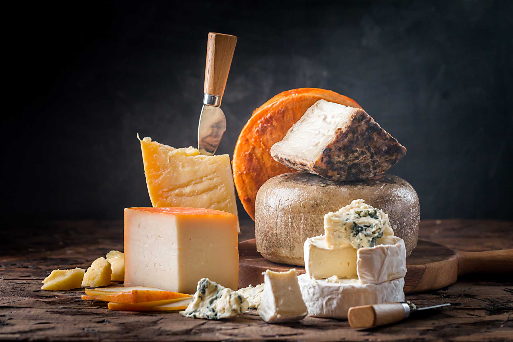 Piezas de diferentes tipos de queso sobre tabla de madera 